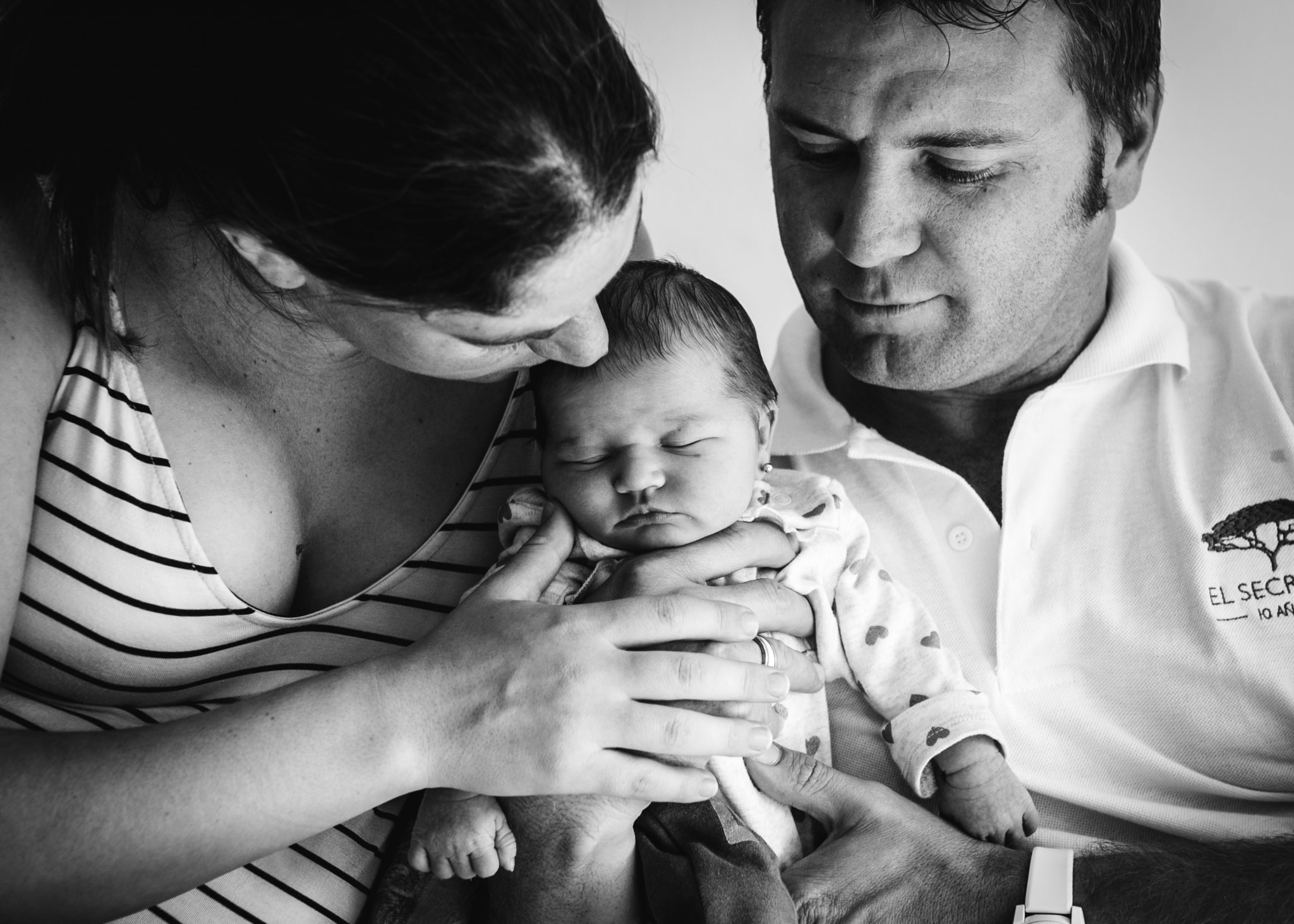 Portrait of a small family, black and white. Mom and dad are holding their newborn girl.
