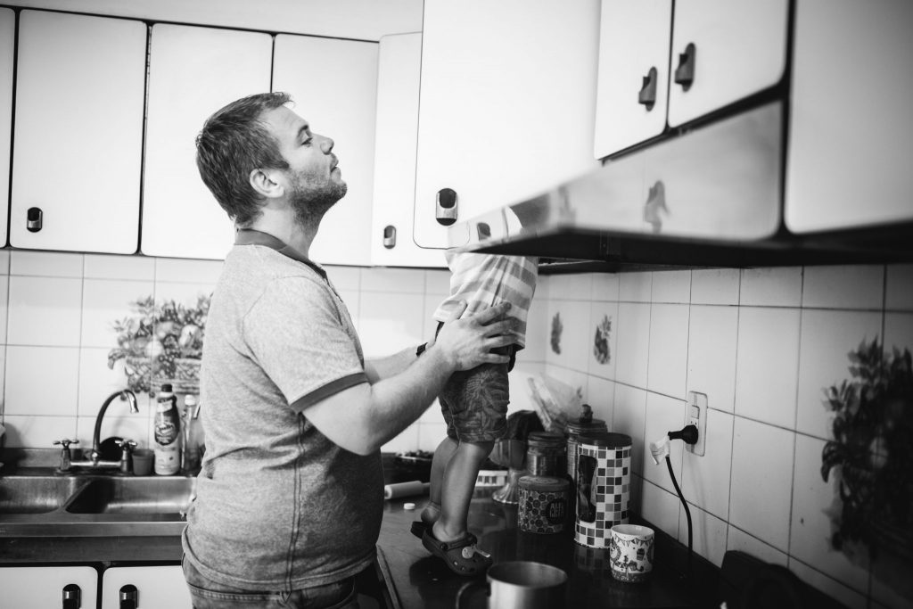 Toddler helping her dad to make breakfast on the countertop of their home, having fun during their spontaneous and honest photoshoot