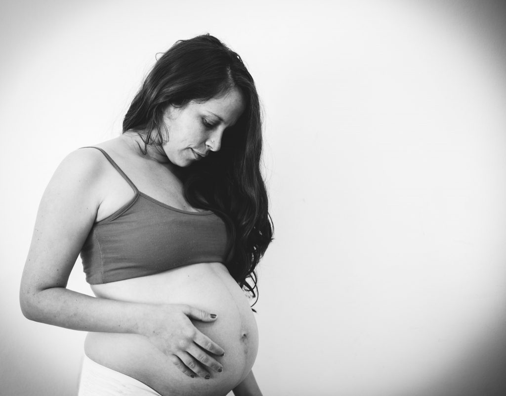 Selfportrait with a big pregnant belly at my own house, looking down a little shy because I wasn't feeling very happy with my body