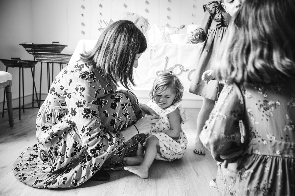 Mom conforting her toddler who is crying in her birthday party in Amsterdam