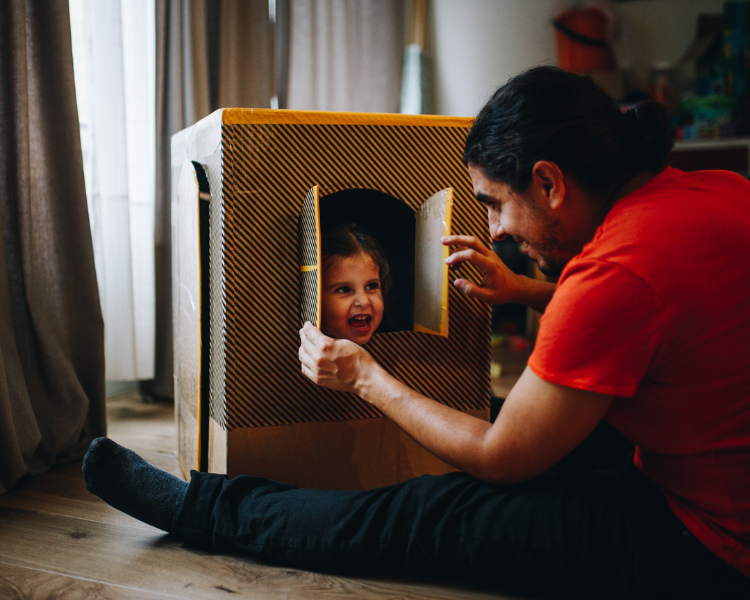 Little girl inside a cardboard house, playing with her father during a Documentary Family Photoshoot in Amsterdam