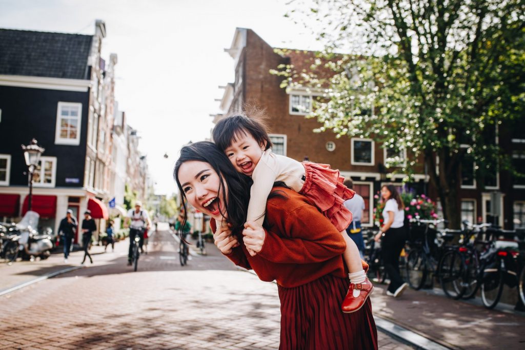 mom and her child on her back, playing on the streets of Amsterdam on a Saturday morning