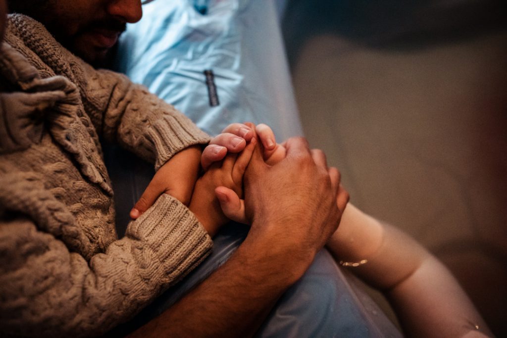 Dad, child and woman holding hands next to the pool while she's in labor.