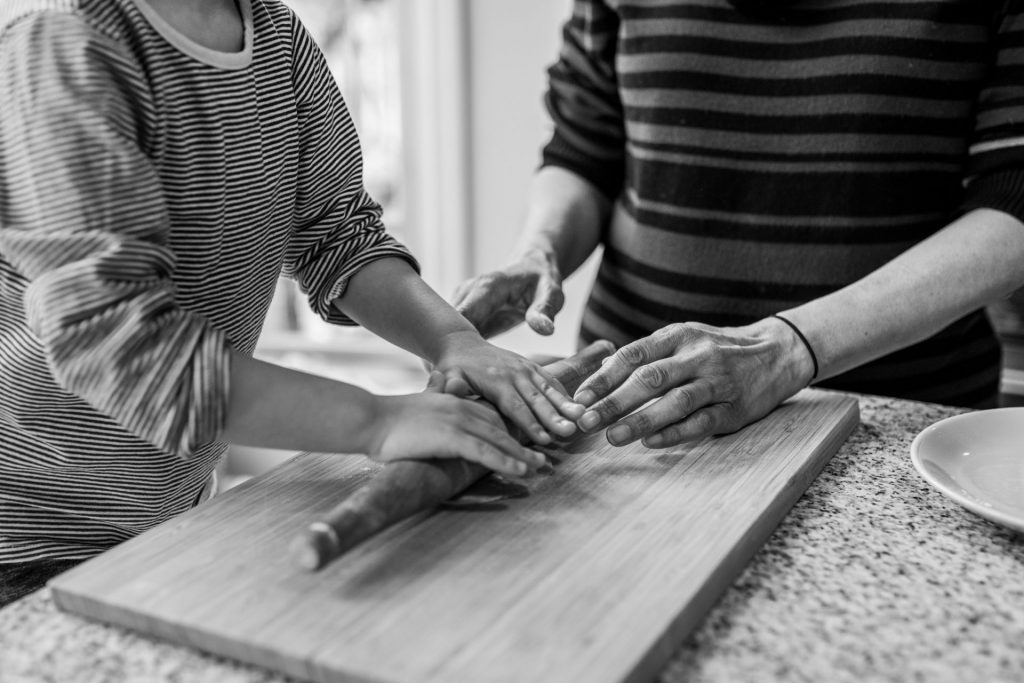 grandmother and grandson's hands using a rolling pin to roll out the dough. Black and white picture. Details.