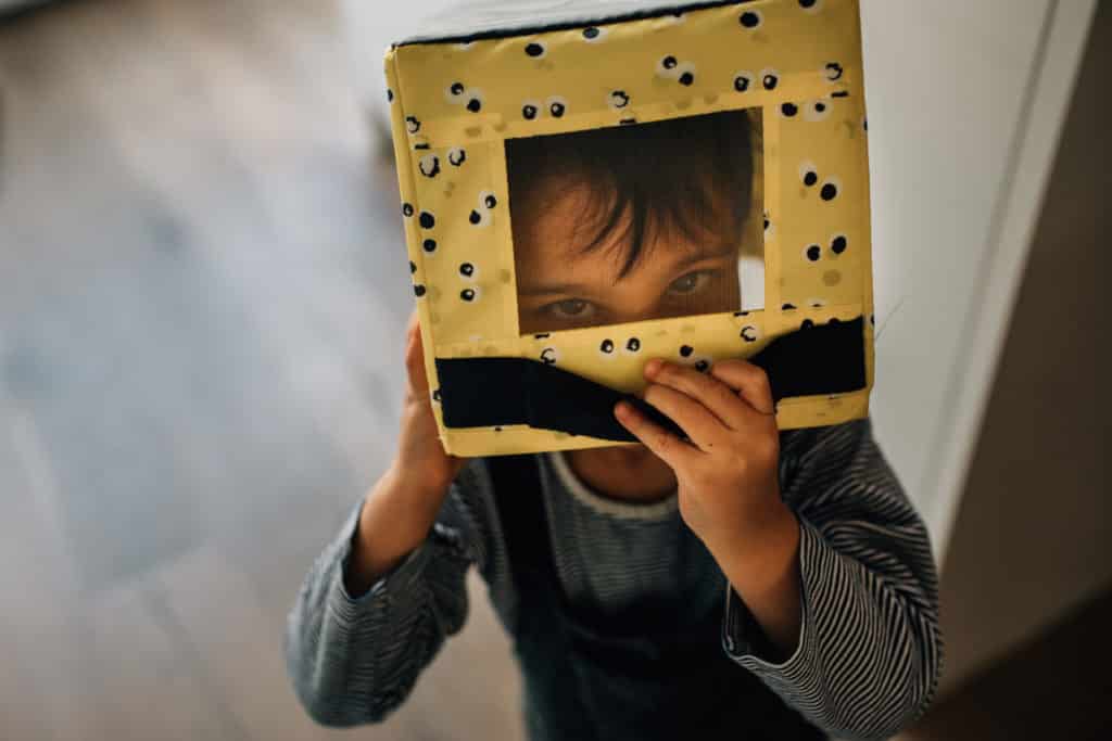 Child with a box on his head, his eyes are looking at the camera. Amsterdam portrait.