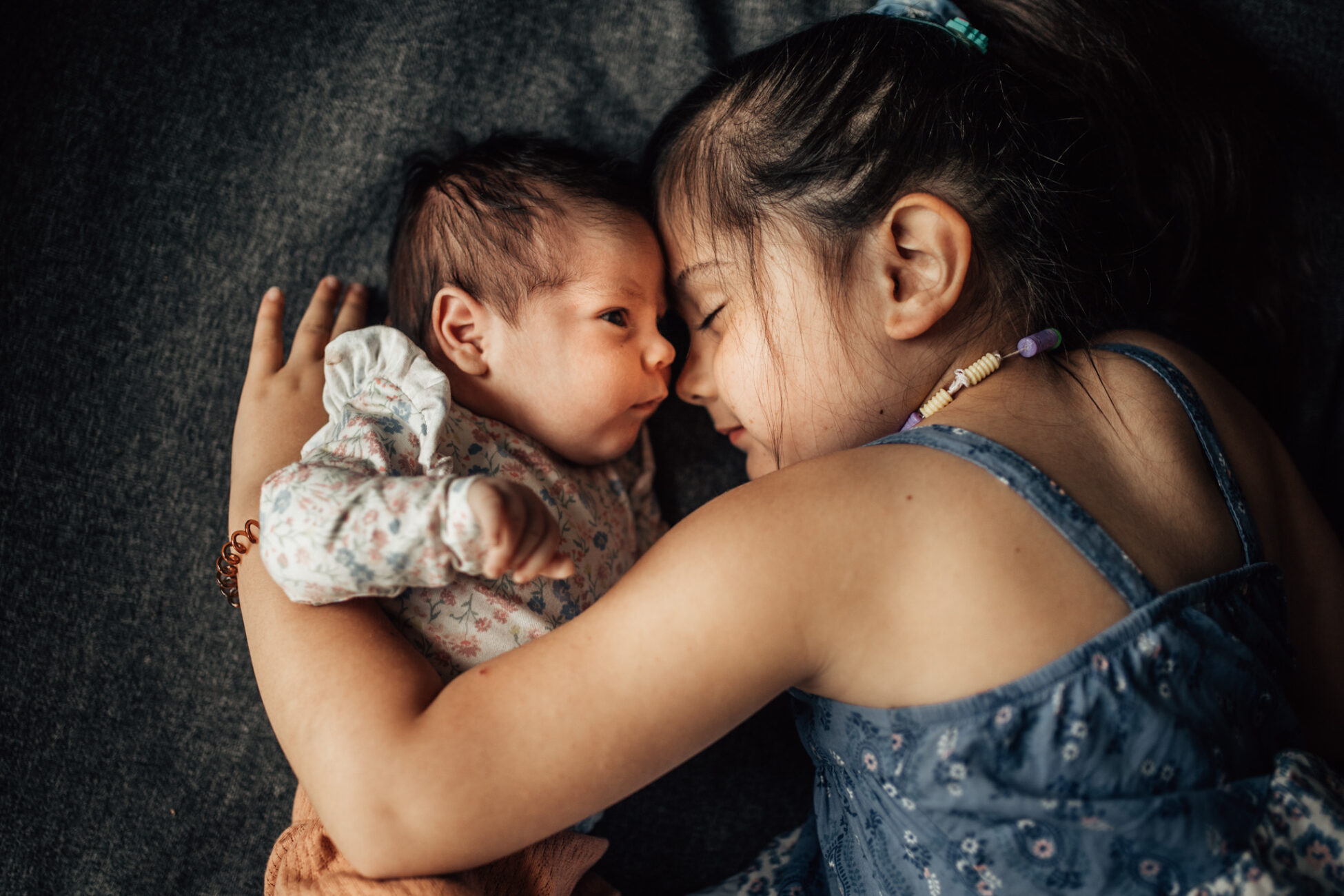 Newborn and her older sister lying next to each other.