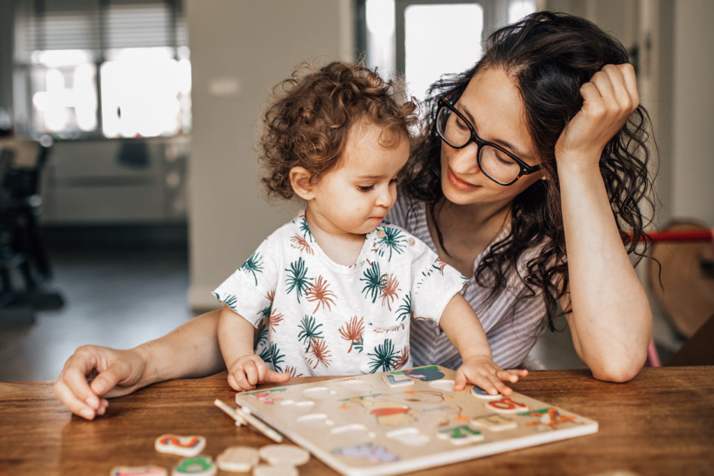 Mom and her little toddler playing with a puzzle in their livingroom