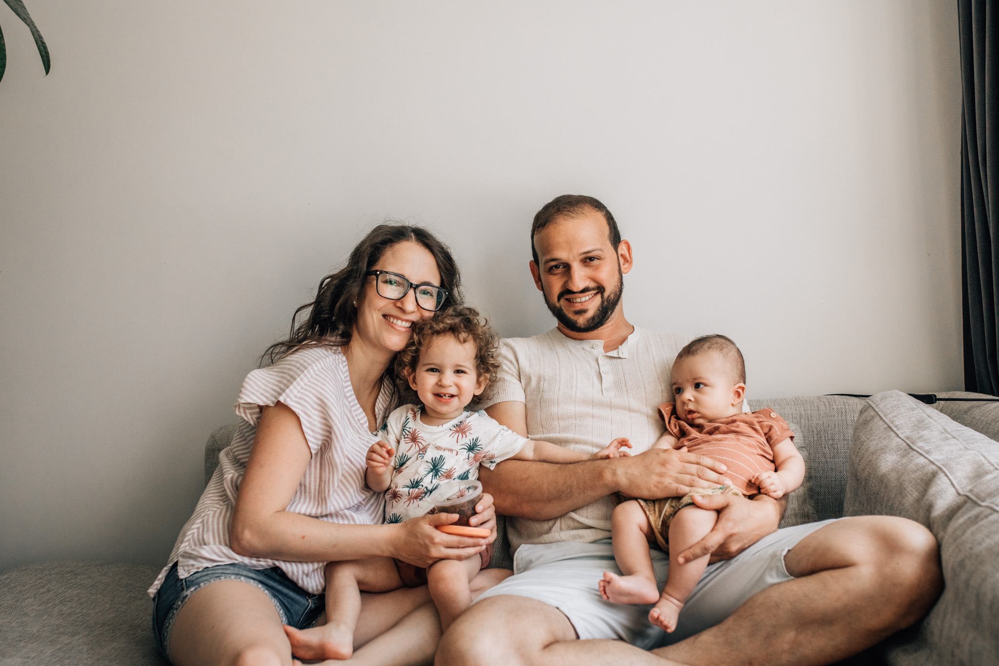 Family photography in Amsterdam, Portrait of a family of four sitting on the couch of their livingroom.