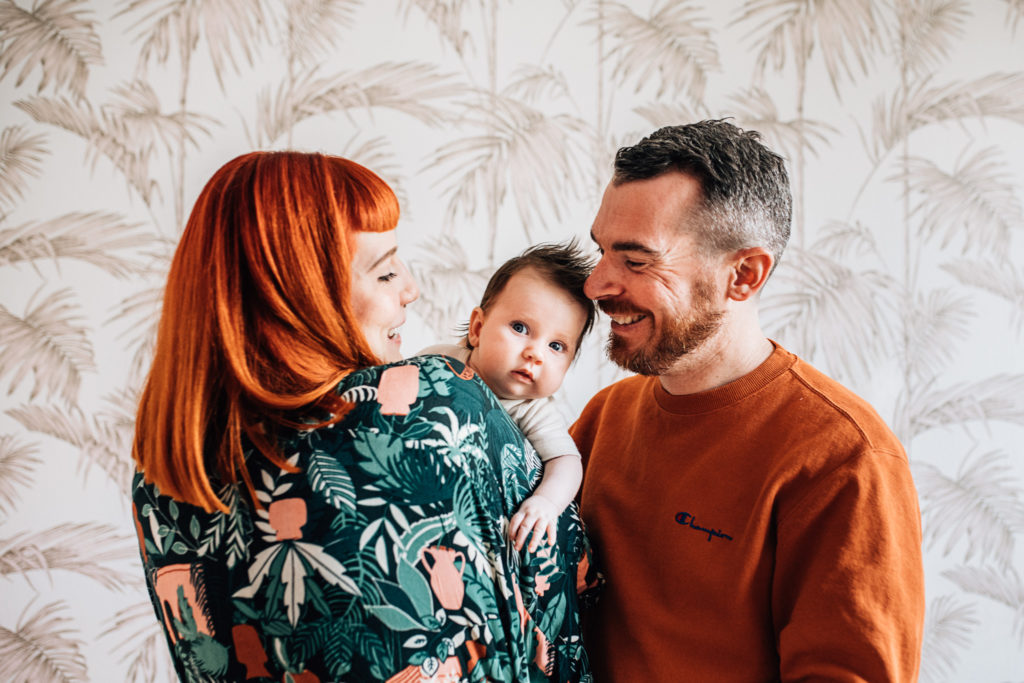 mom and dad holding their newborn baby, smiling
