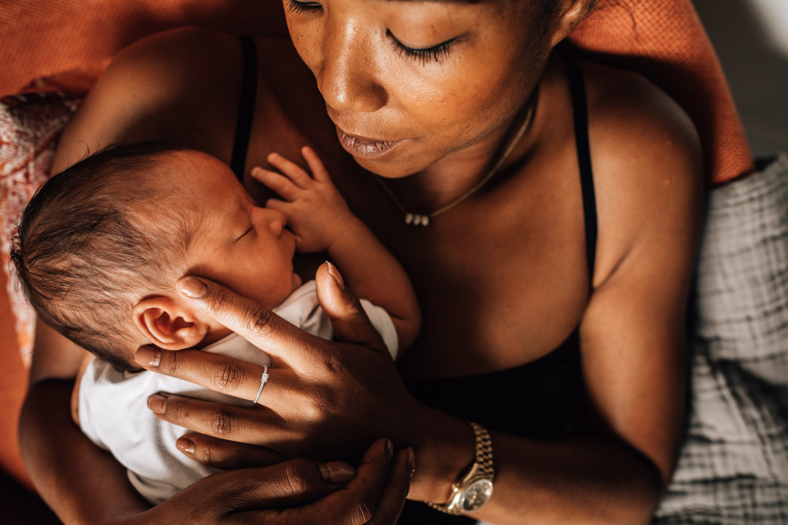 mom holding her newborn baby on her chest, while caressing him