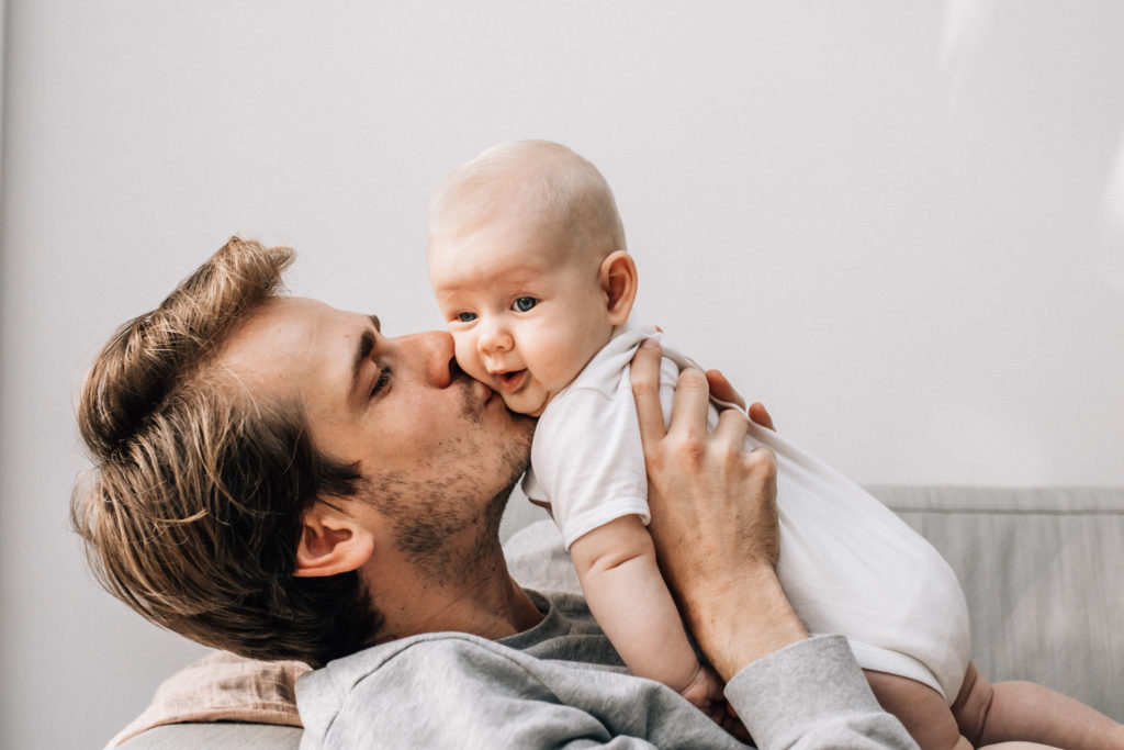 dad holding and kissing his baby daughter on her cheek
