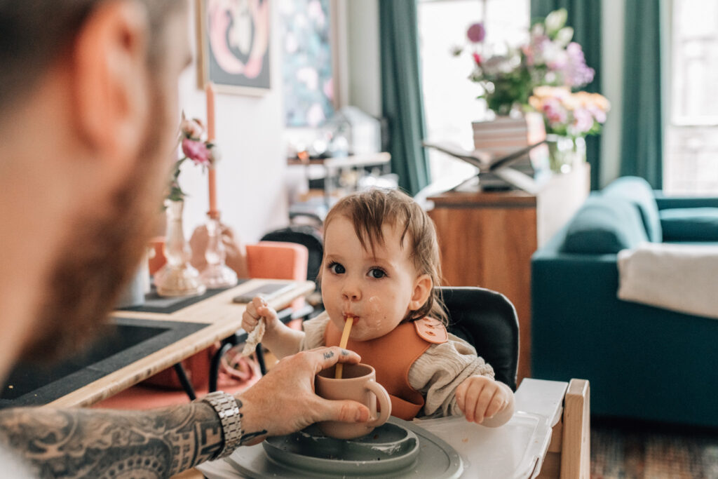 Portrait of a toddler drinking water from a cup with a straw.