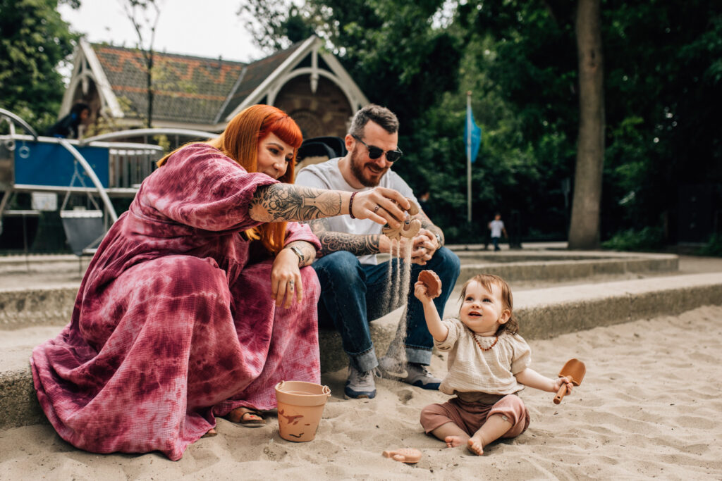 Family of three playing with sand in the Sarphatipark.