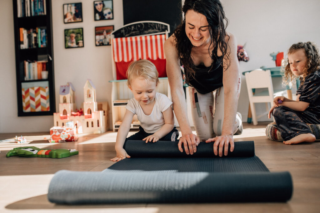 Mom and kid rolling a yoga mat at their home on a family photography session in Amsterdam, The Netherlands
